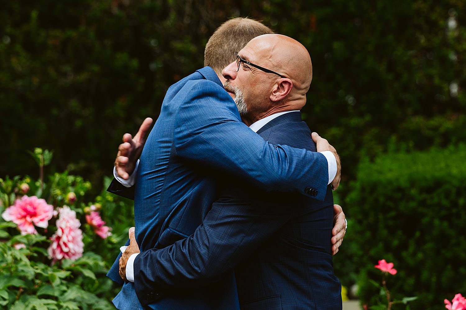 Father of the bride and groom hugging