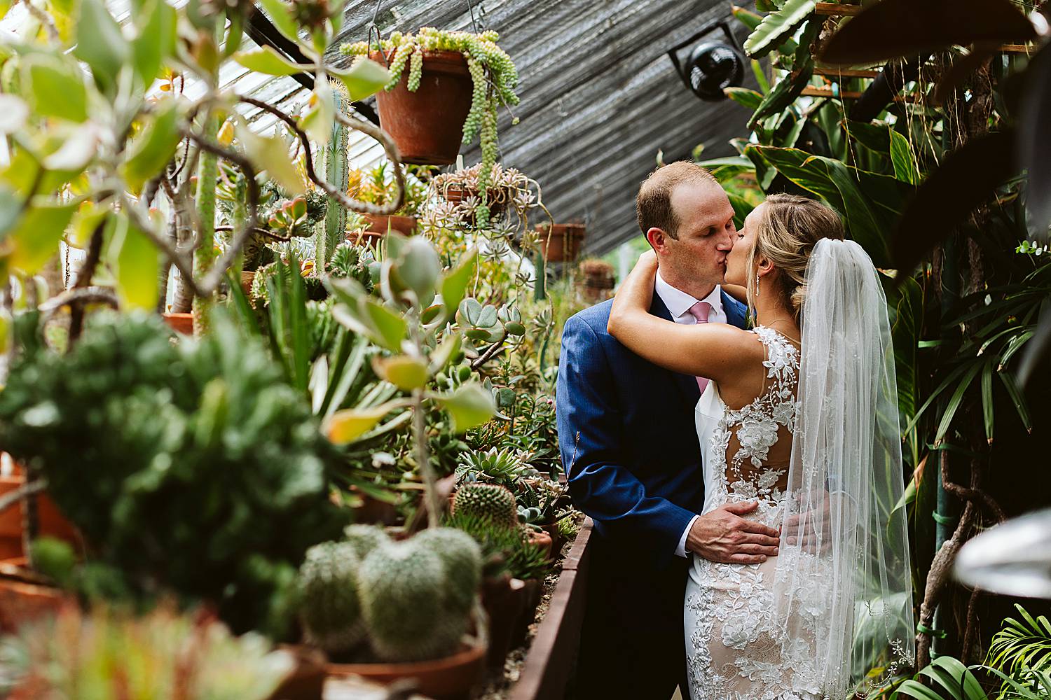 Portrait of a bride and groom kissing in a greenhouse