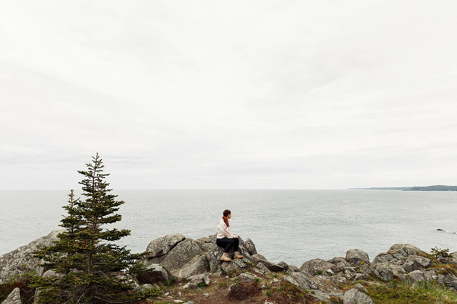 Lubec, Maine photographer Hailey Crabtree sitting on cliffs and looking out at ocean