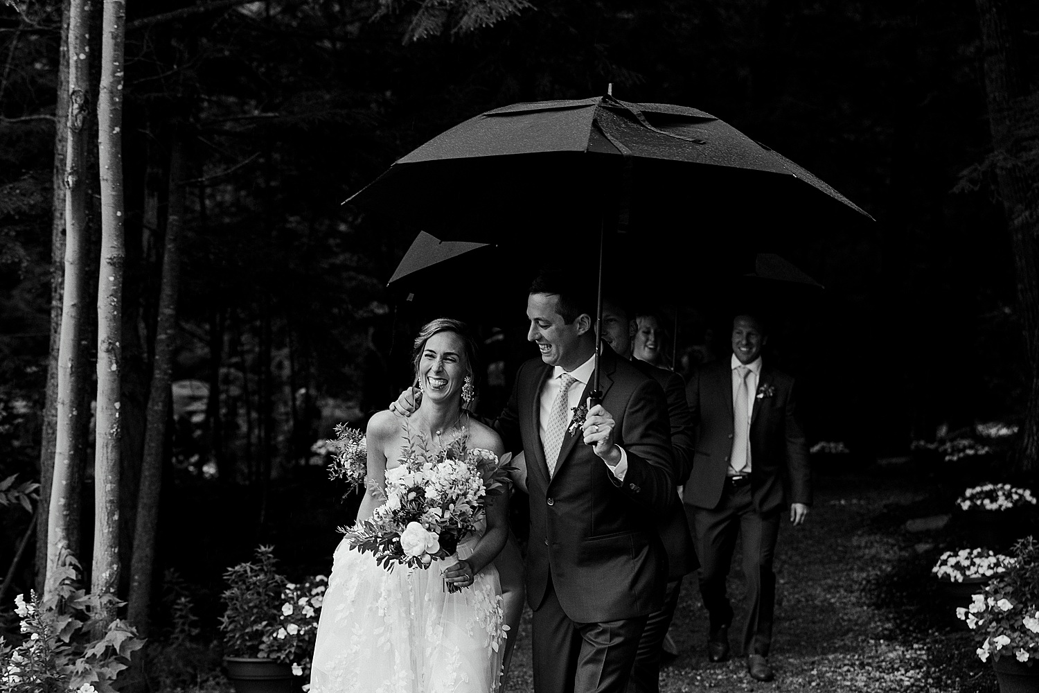 Bride and groom smiling under umbrellas at Maine wedding