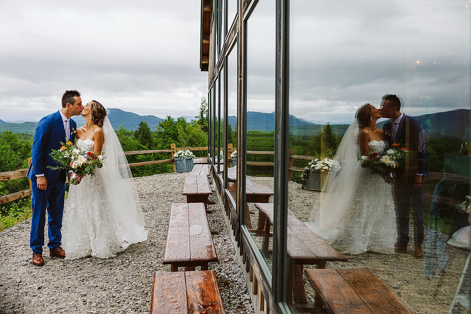bride and groom kissing with their reflections on barn windows at Maine wedding at Granite Ridge Estate & Barn