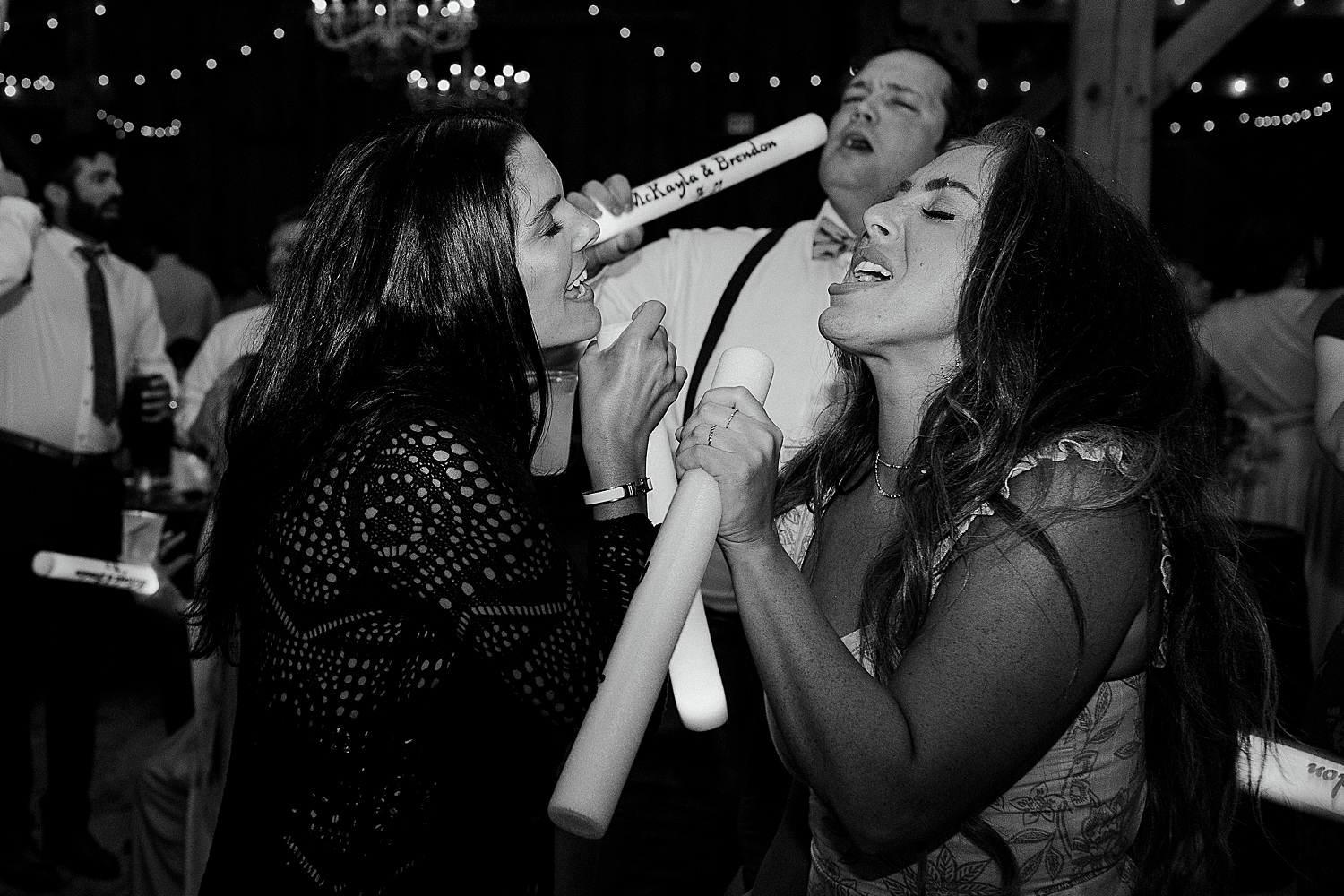 women using glow sticks as microphones at Maine wedding