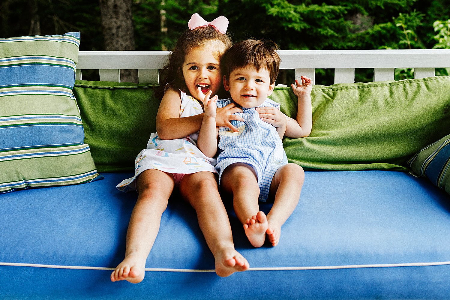 two kids on porch swing during summer portraits in Sargentville, Maine