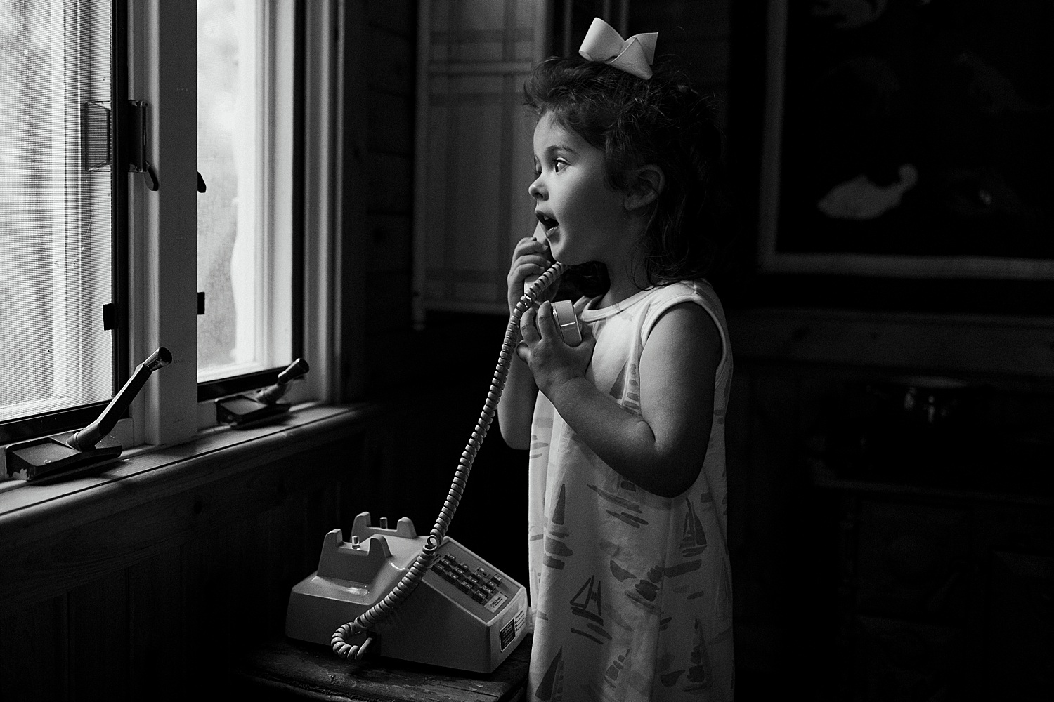 little girl on telephone in her playhouse during summer portraits in Sargentville, Maine