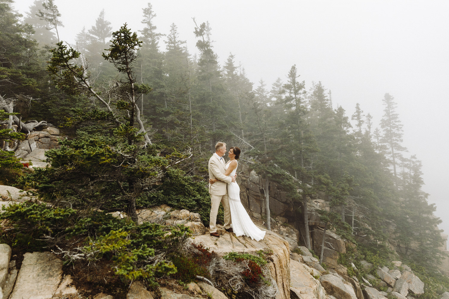 couple standing on cliff during foggy elopement in Acadia National Park