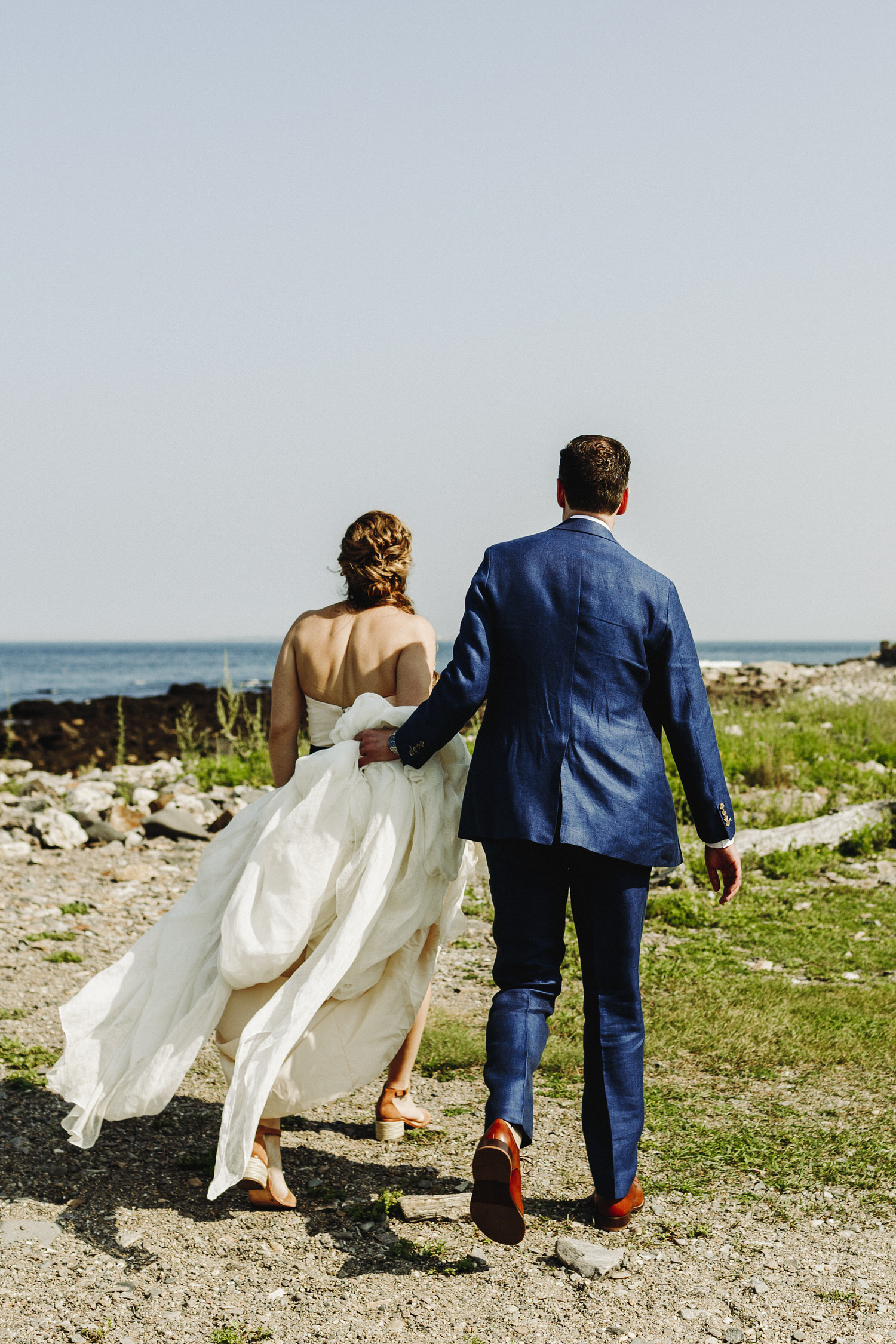 bride and groom walking by the ocean during wedding at Seacoast Science Center in Rye, NH