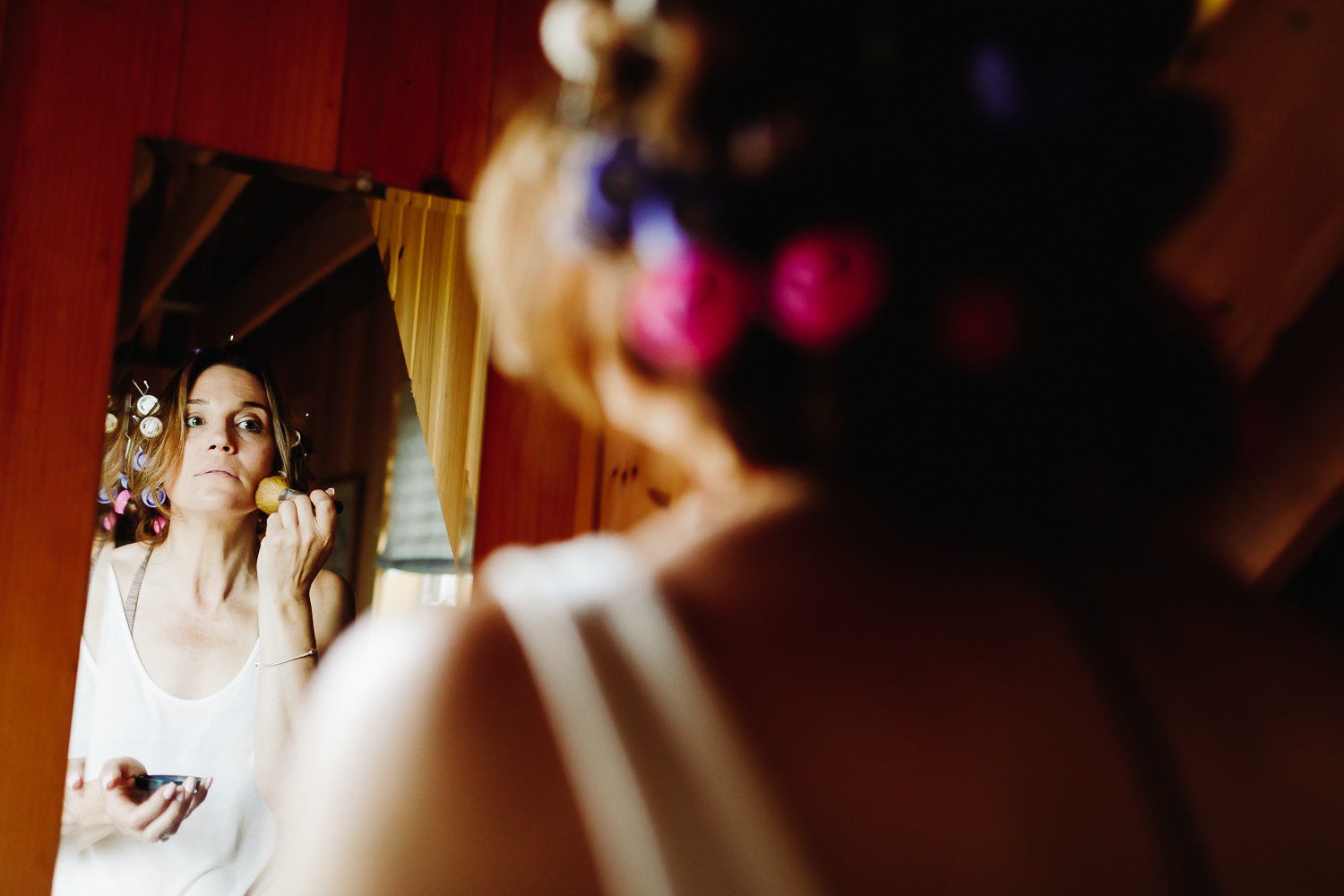 bride putting on makeup at backyard wedding in Northport, Maine