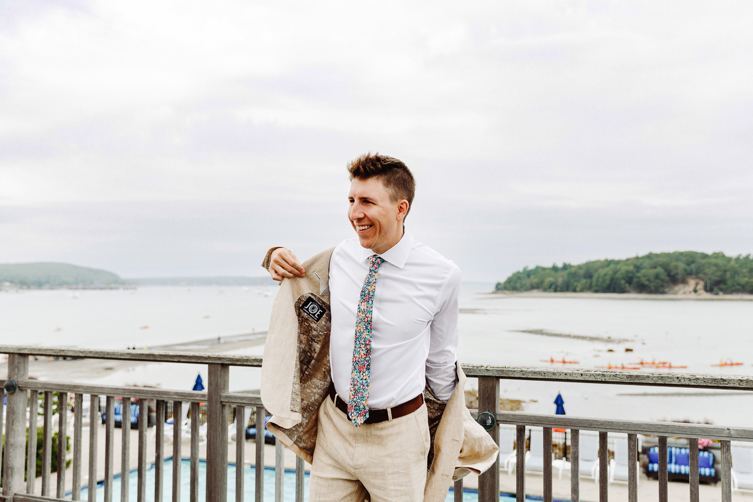 groom putting on his suit jacket by the ocean