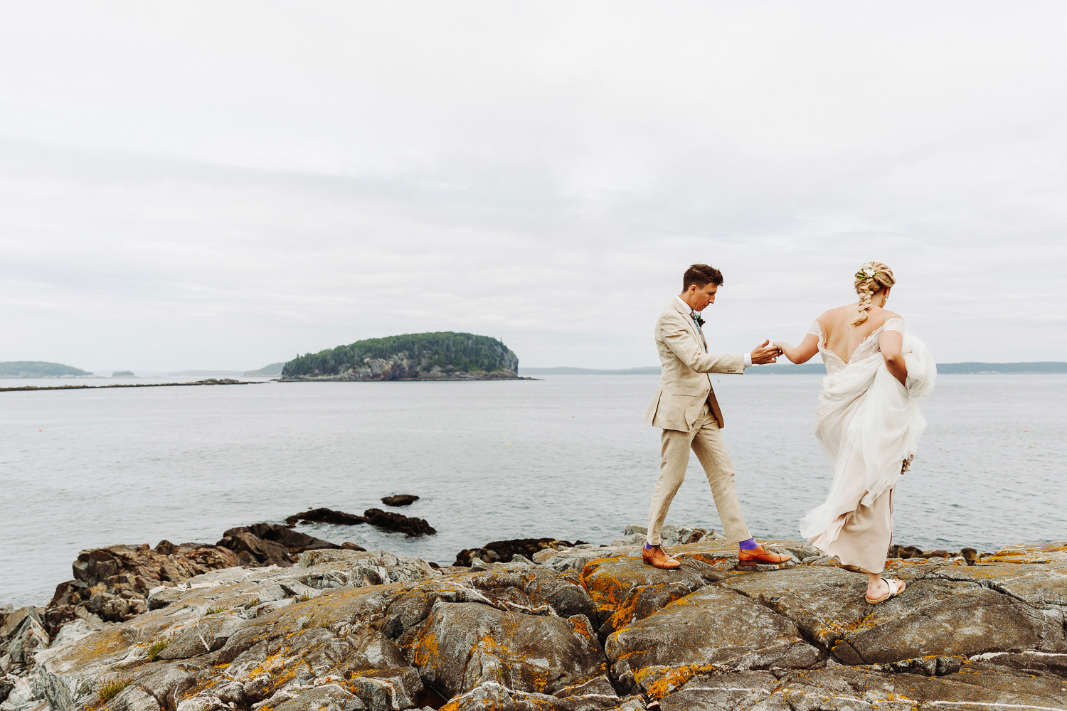 bride and groom walking together on cliffs in Bar Harbor