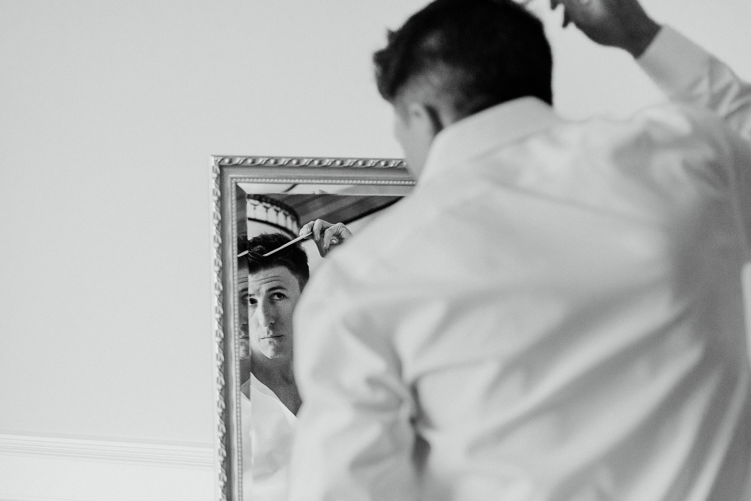 groom fixing his hair in mirror