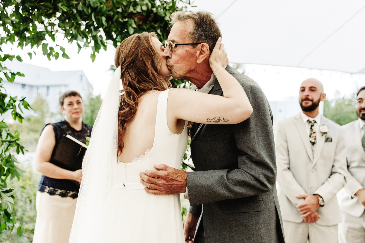 Bride kissing her father on the cheek during wedding ceremony