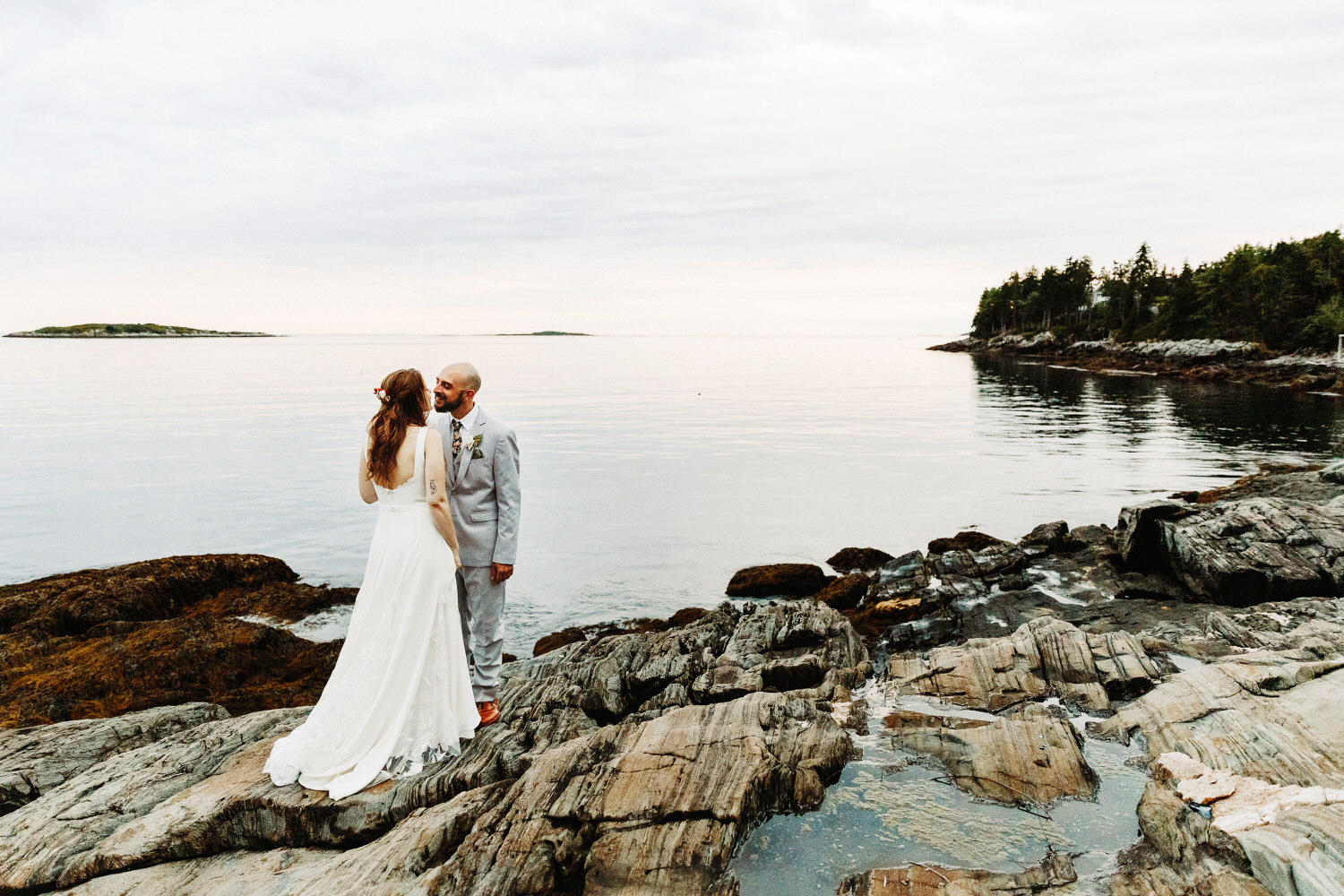 Bride and groom standing on cliffs at twilight