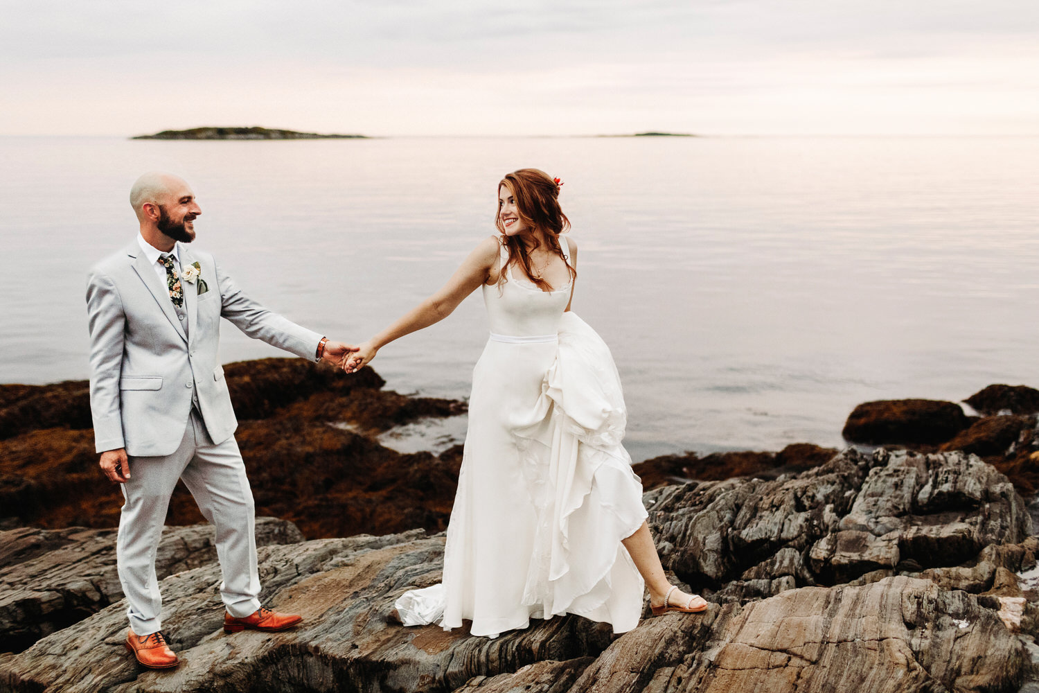 Bride and groom walking together on cliffs in Orr's Island, Maine