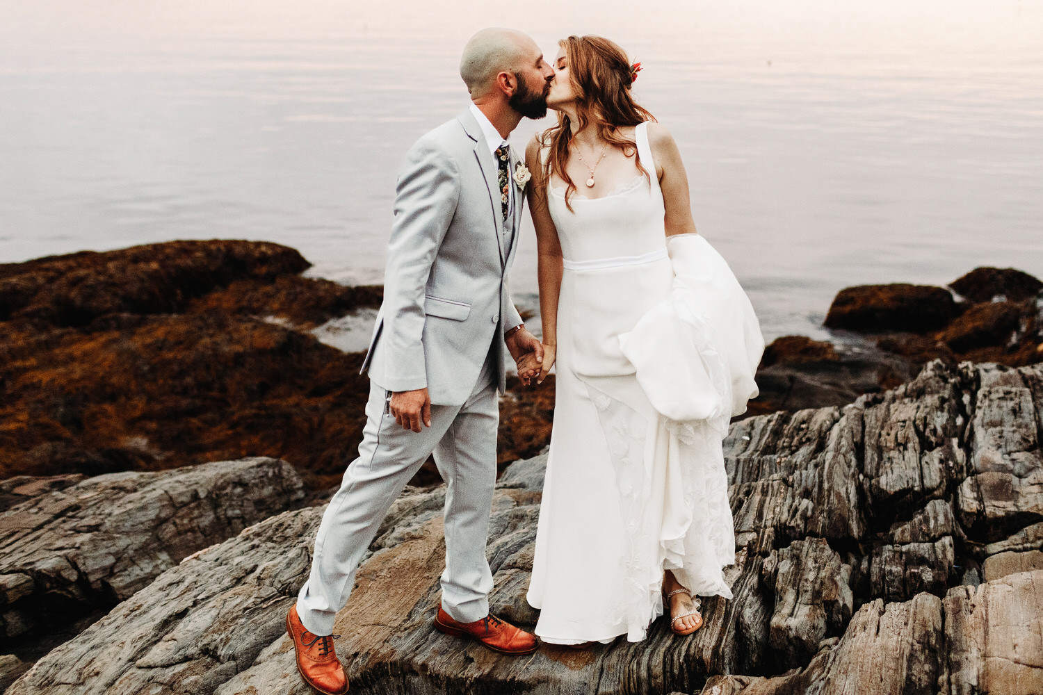 Groom leaning in to kiss bride on cliffs during Orr's Island Maine Wedding