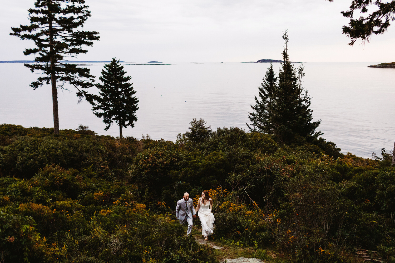 Bride and groom walking together with ocean in the background