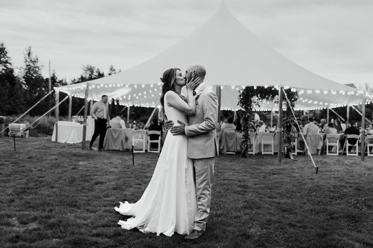 bride and groom kissing in front of wedding tent