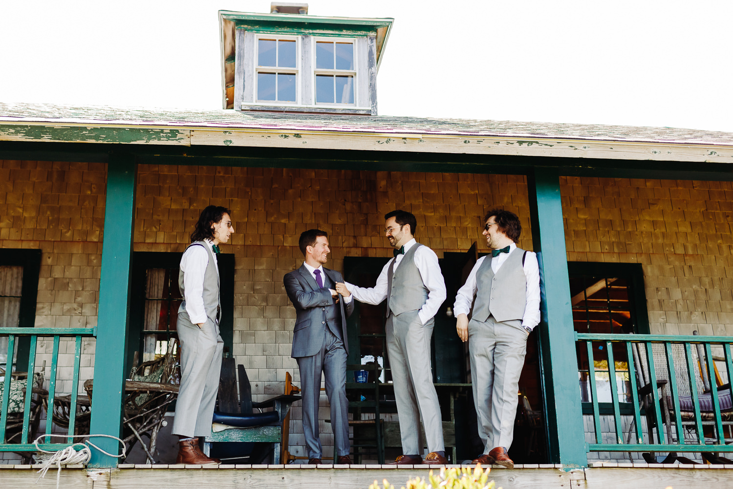 Groom and groomsmen standing on the deck of a cottage on Sutton Island in Maine