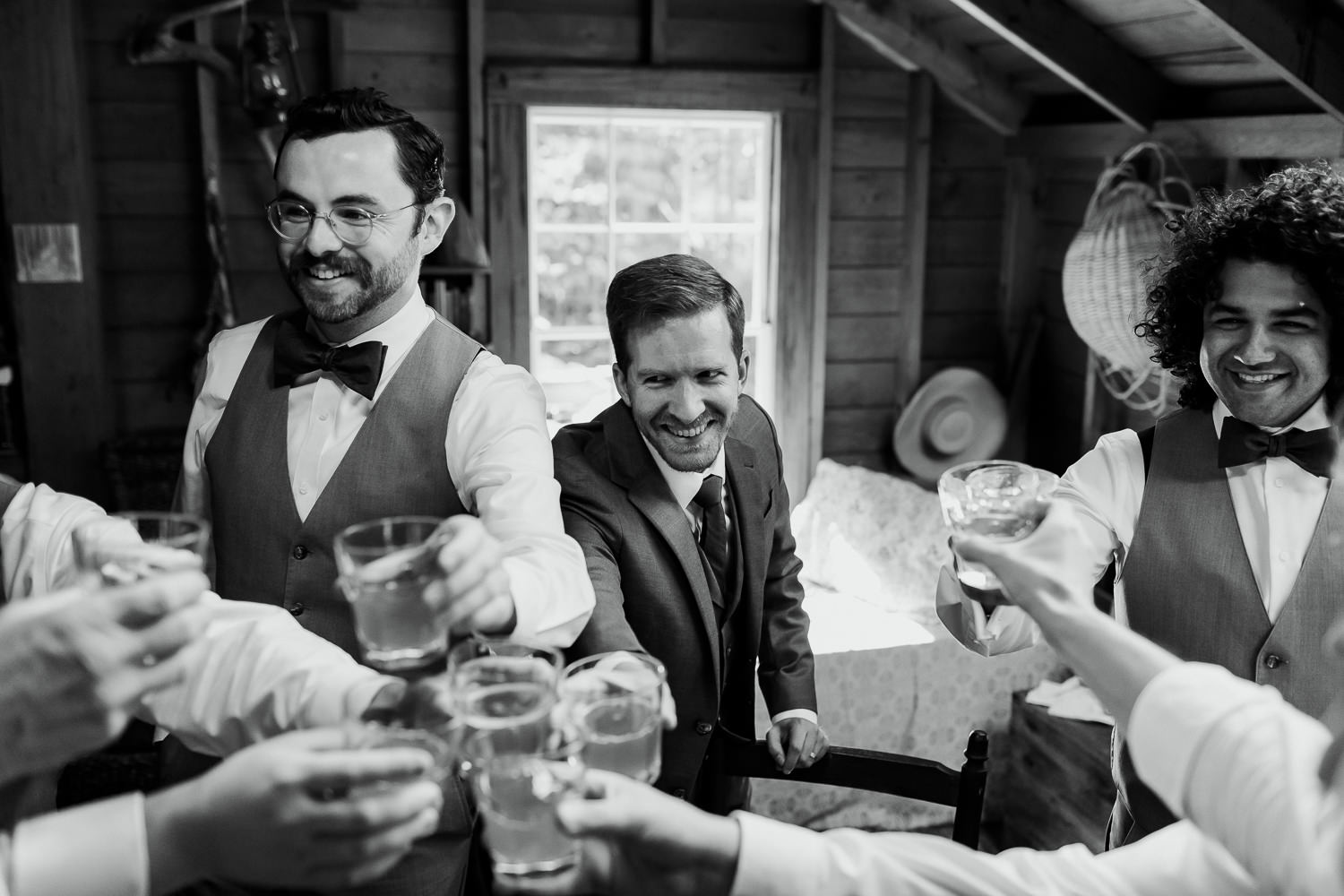 Groom and groomsmen clinking glasses after a toast on Sutton Island