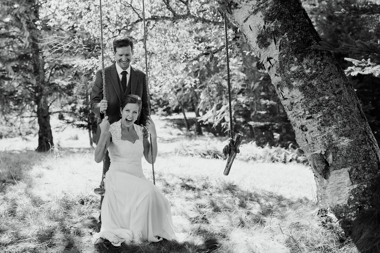 Groom pushing bride on swing during Sutton Island, Maine wedding