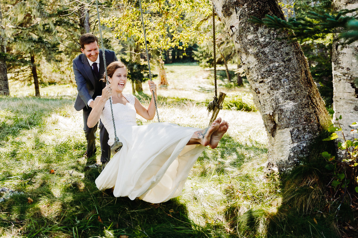 Groom pushes bride on swing at Sutton Island and Bar Harbor Maine wedding