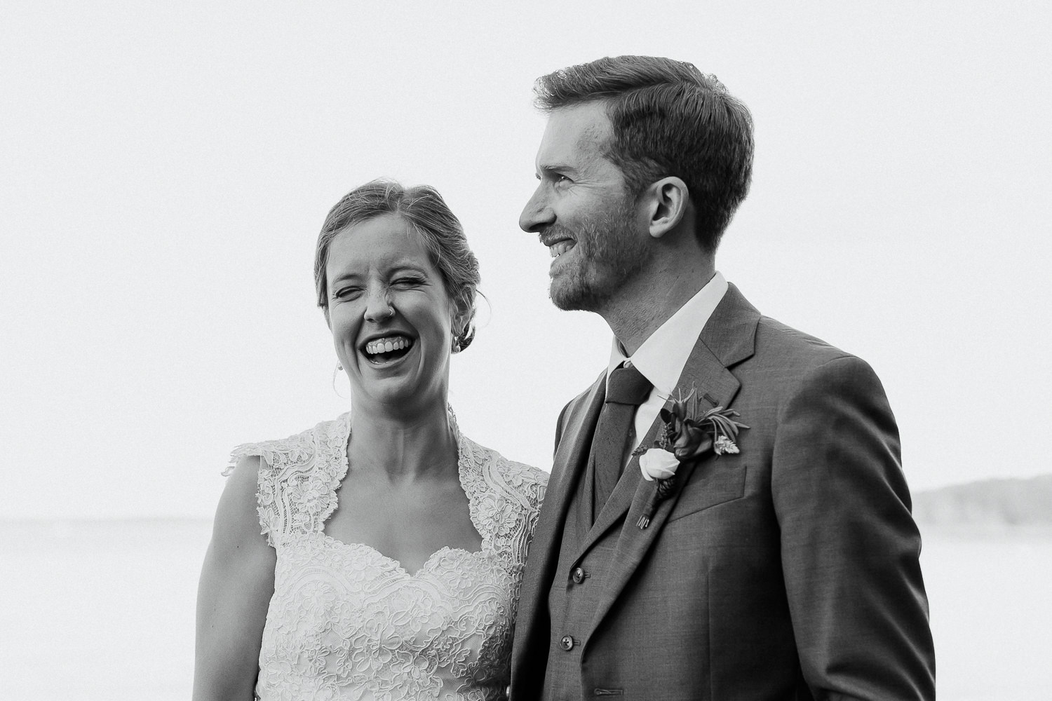 Black and white photo of bride and groom laughing at Sutton Island and Bar Harbor Maine wedding