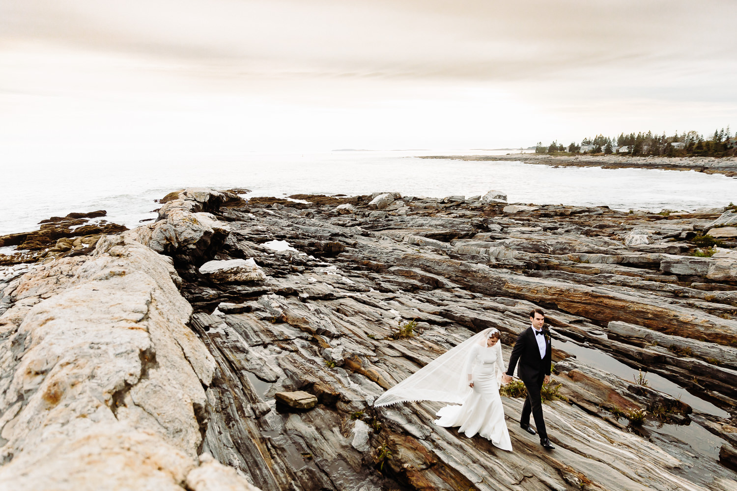 Bride and groom on cliffs at Pemaquid Point Lighthouse during Contented Sole Maine wedding