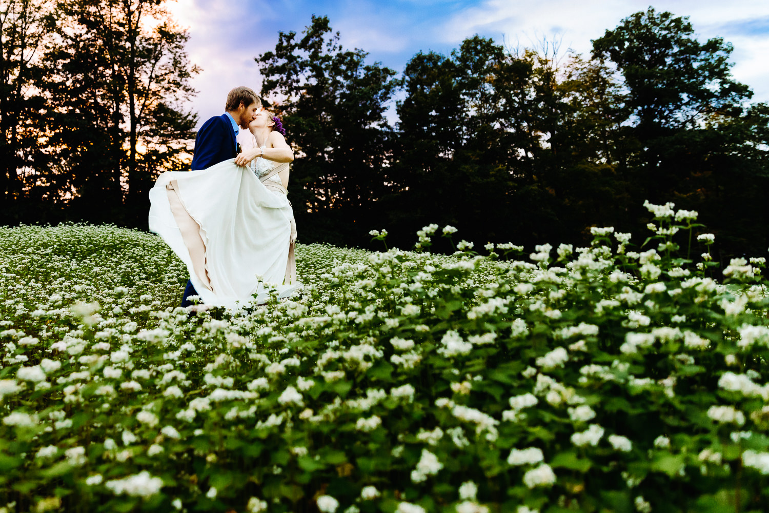bride swishing her wedding dress while kissing groom at Hopkinton NH farm wedding