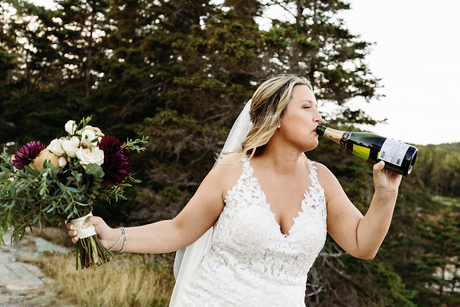 bride chugging champagne at cliffside Acadia elopement