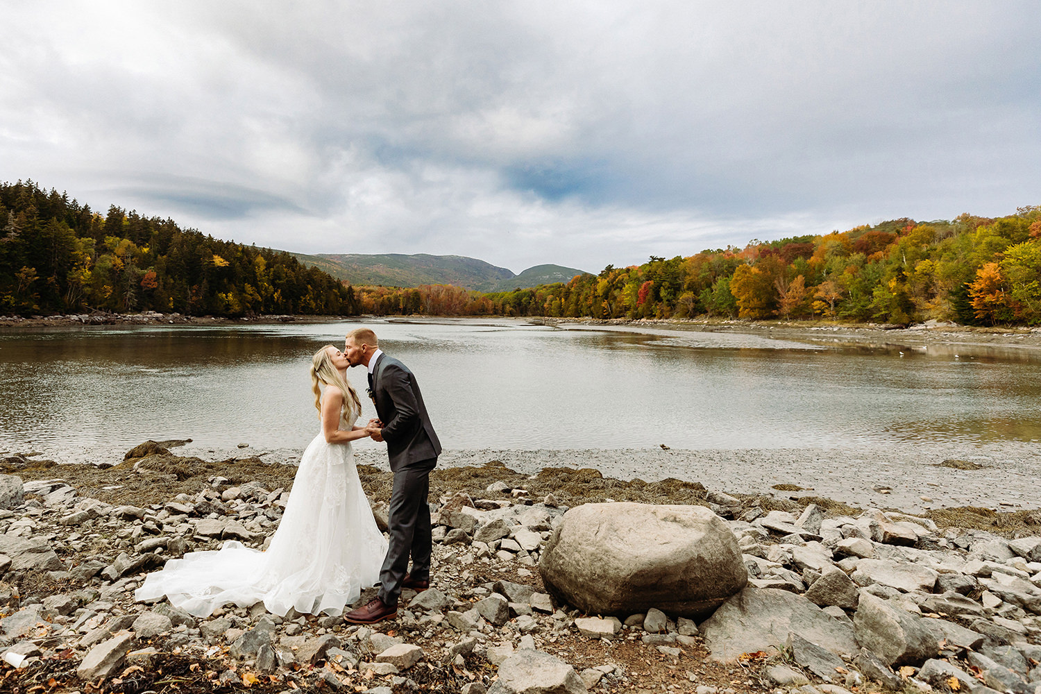 couple kissing with fall foliage behind them during during fall elopement in Acadia National Park