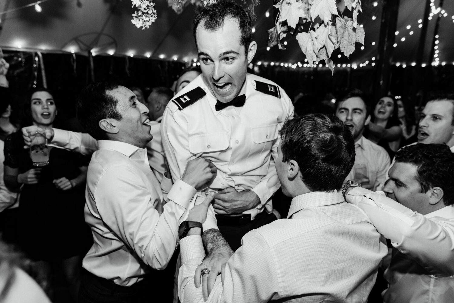groom being lifted in the air by friends during wedding reception