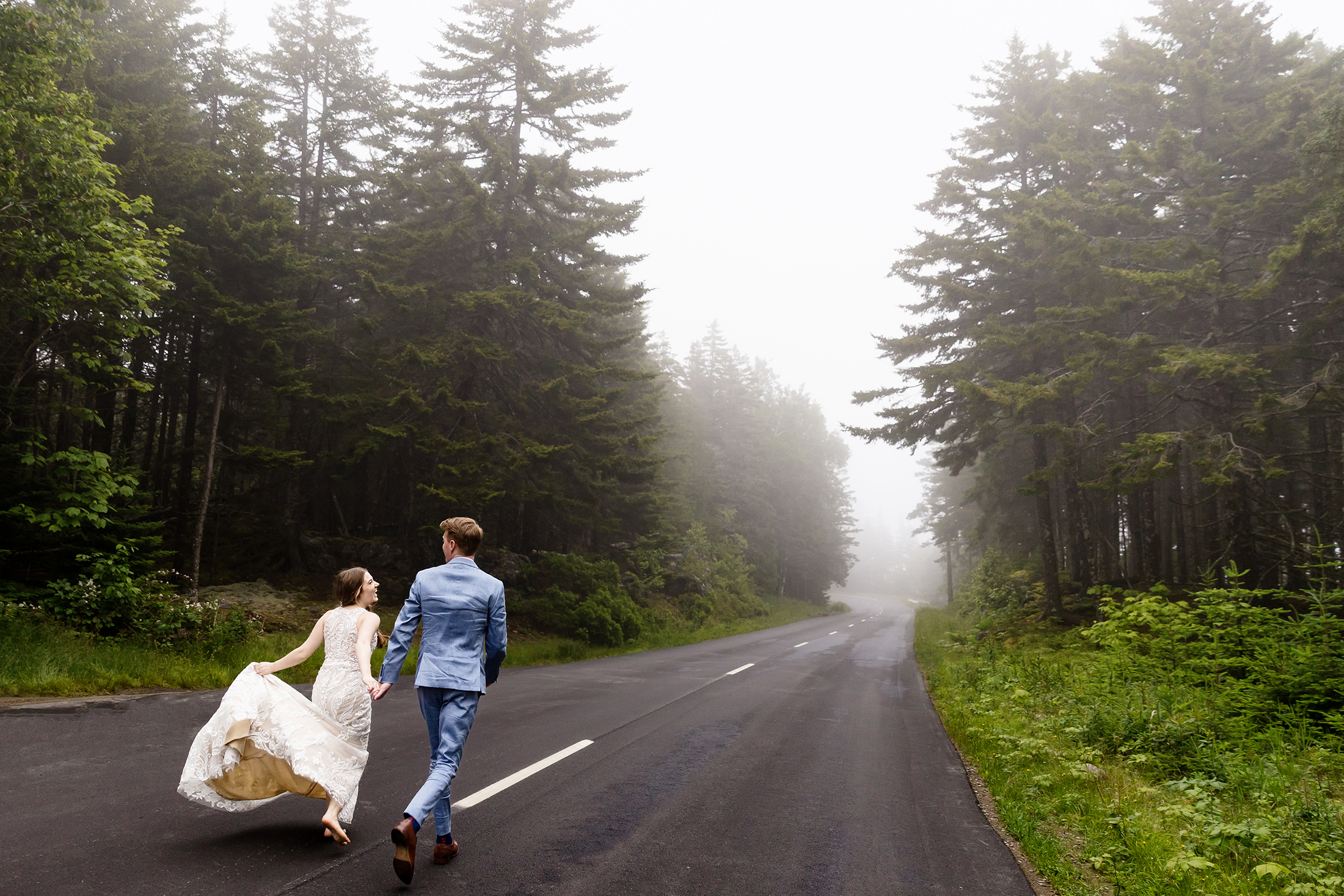 Newlyweds running in Acadia National Park after wedding portrait in Acadia National Park after Under Canvas Acadia wedding in Surry Maine