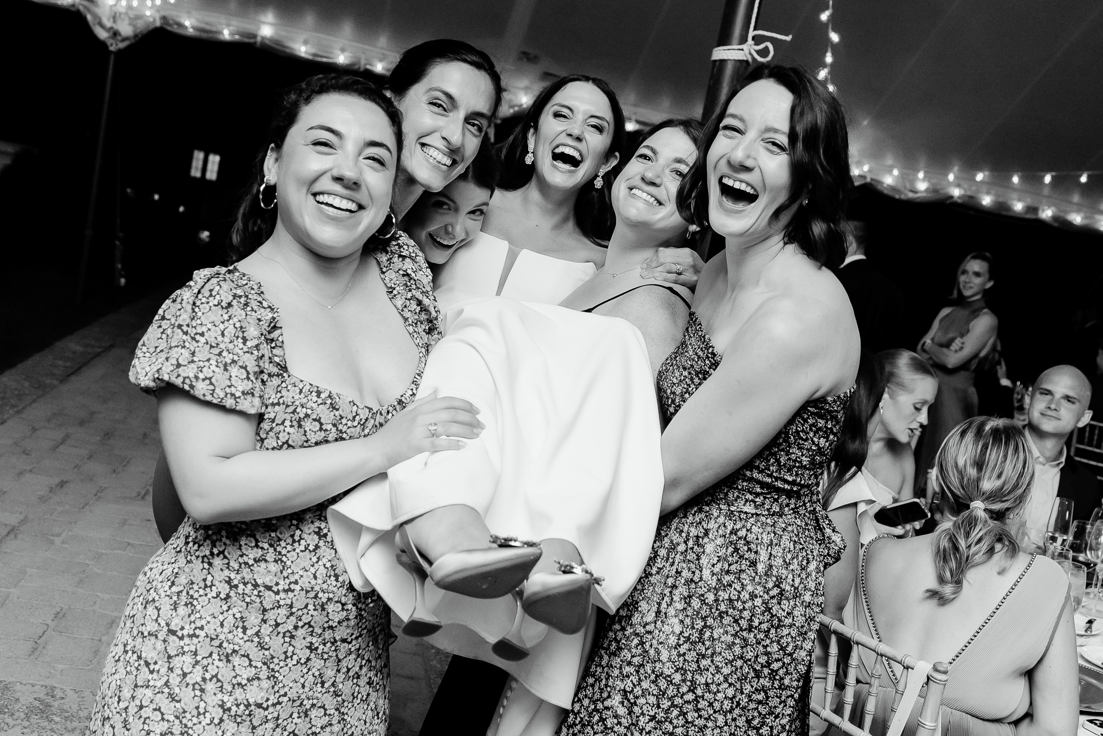 bride's friends lifting her in the air during tented Bar Harbor wedding at Bar Harbor Club