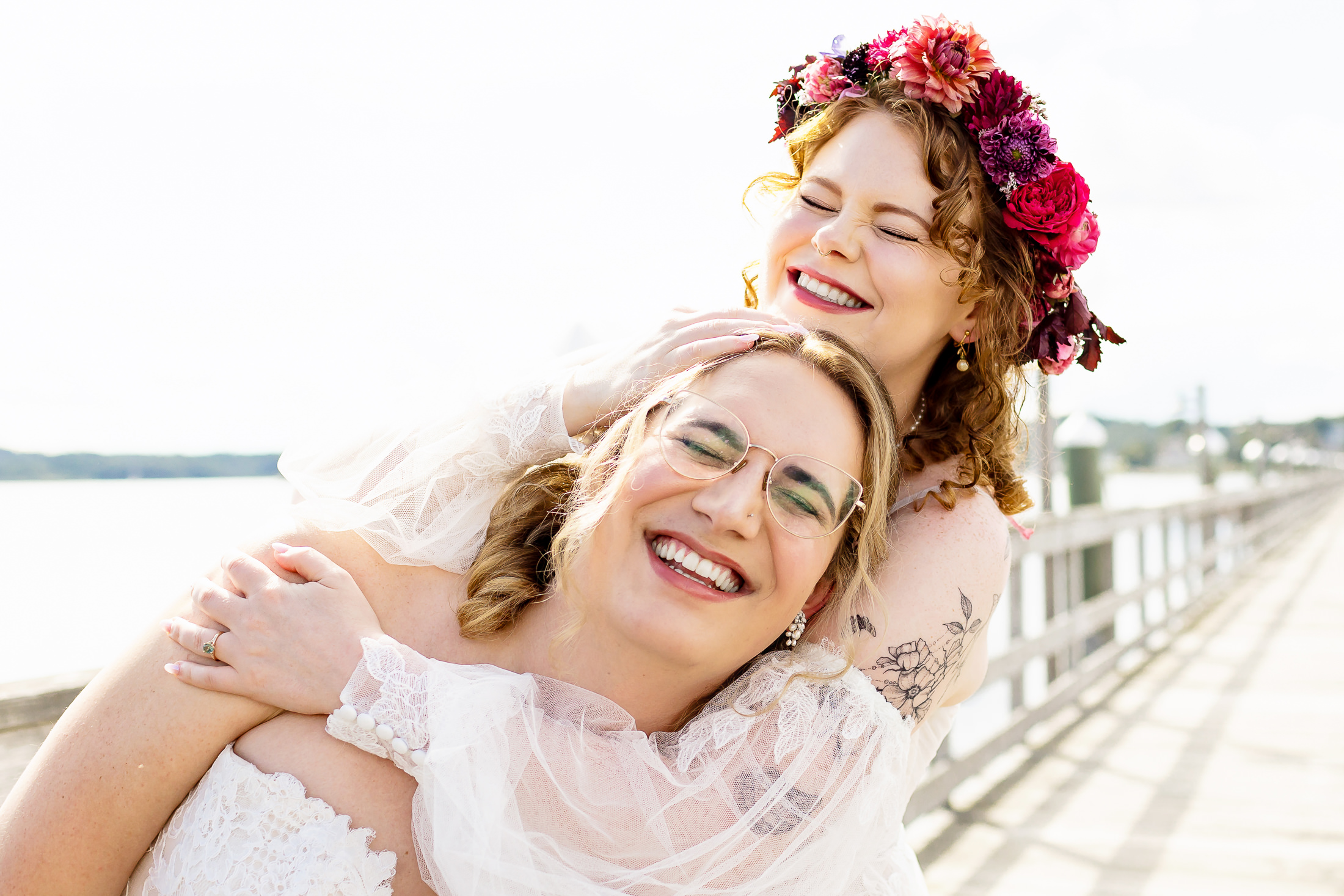Two brides laughing together at their Edgecomb Maine wedding at Glidden Point Oyster Farms