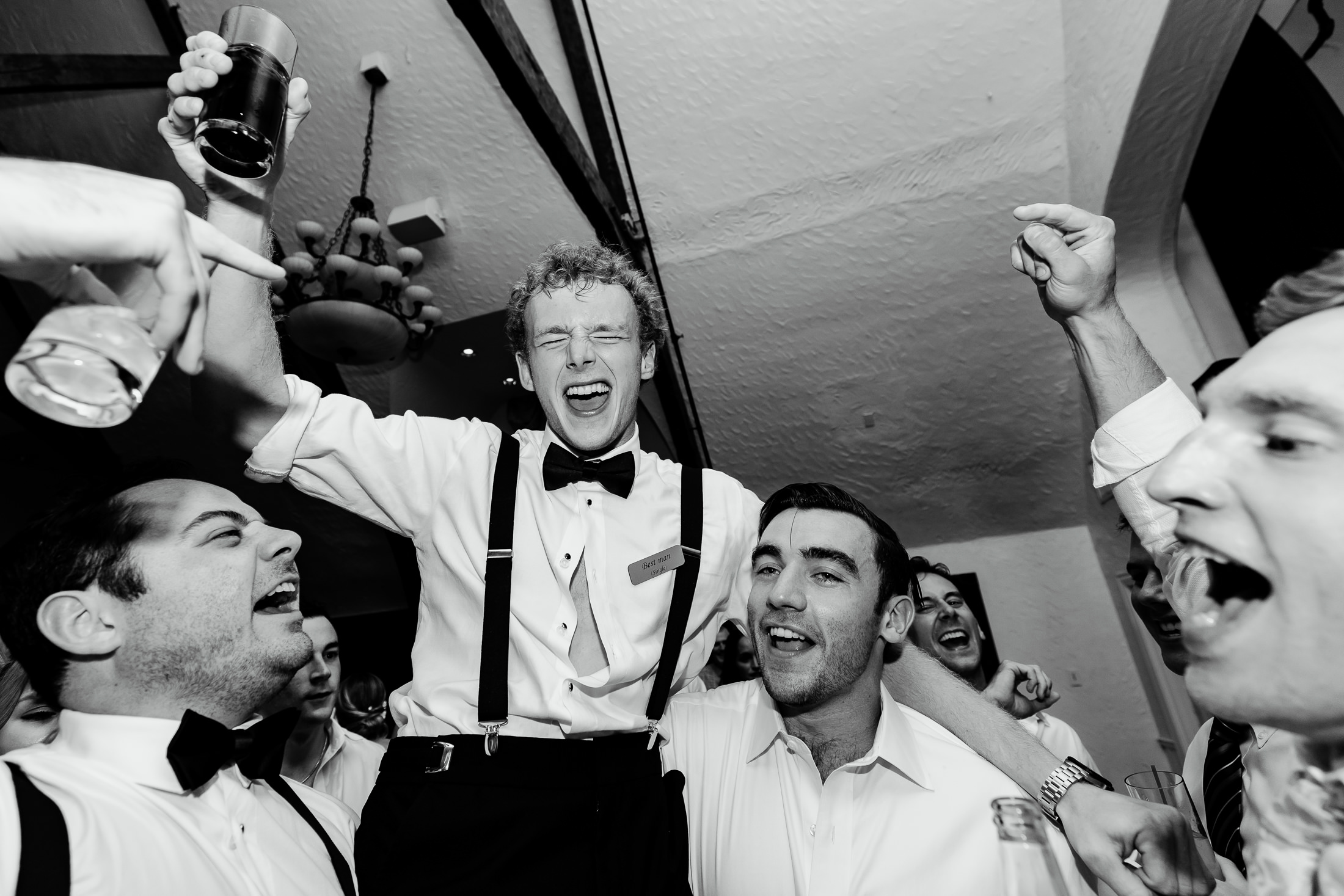 best man is lifted in the air by other groomsmen at stormy Bar Harbor wedding