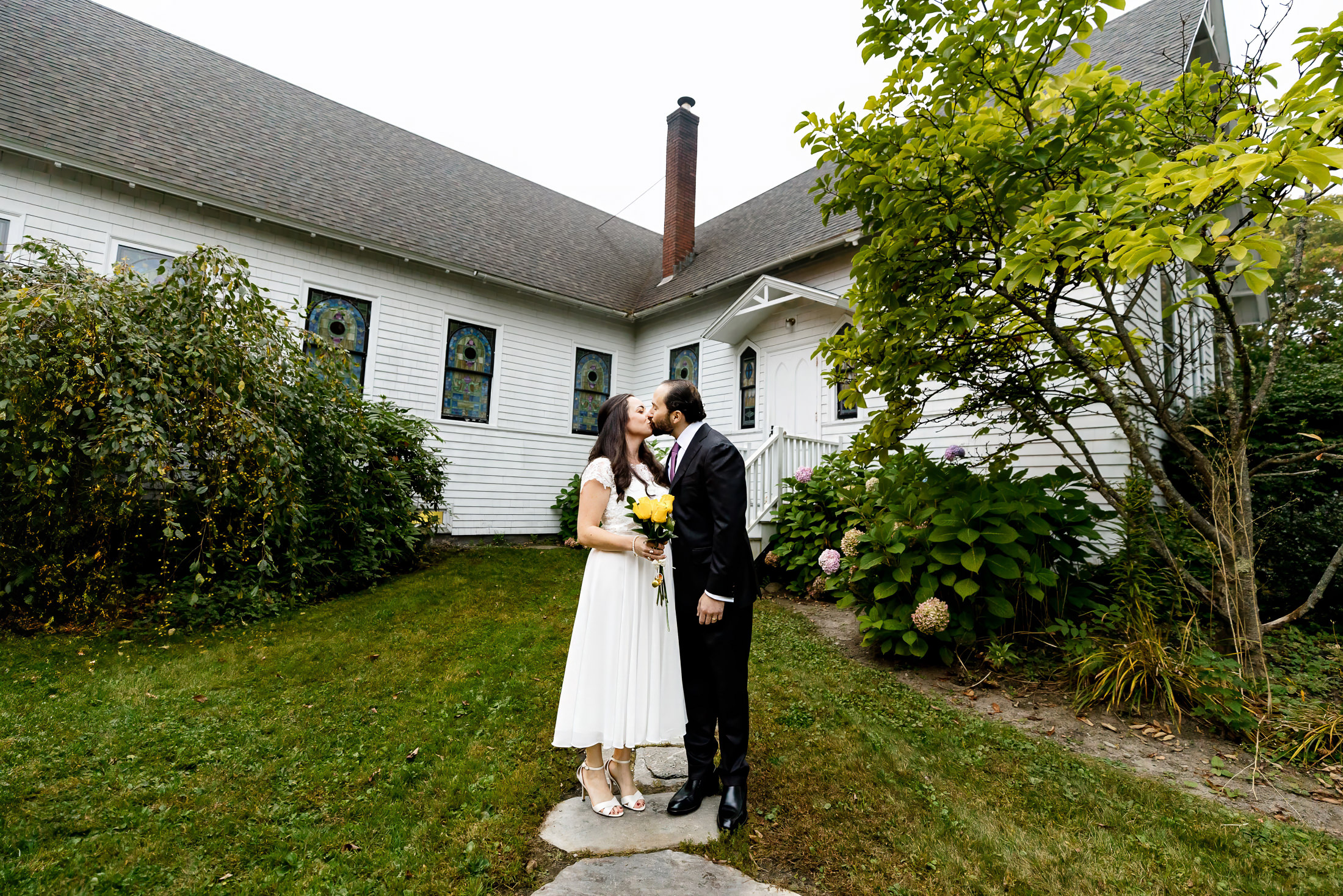 Couple kissing in front of church after Camden Maine wedding ceremony