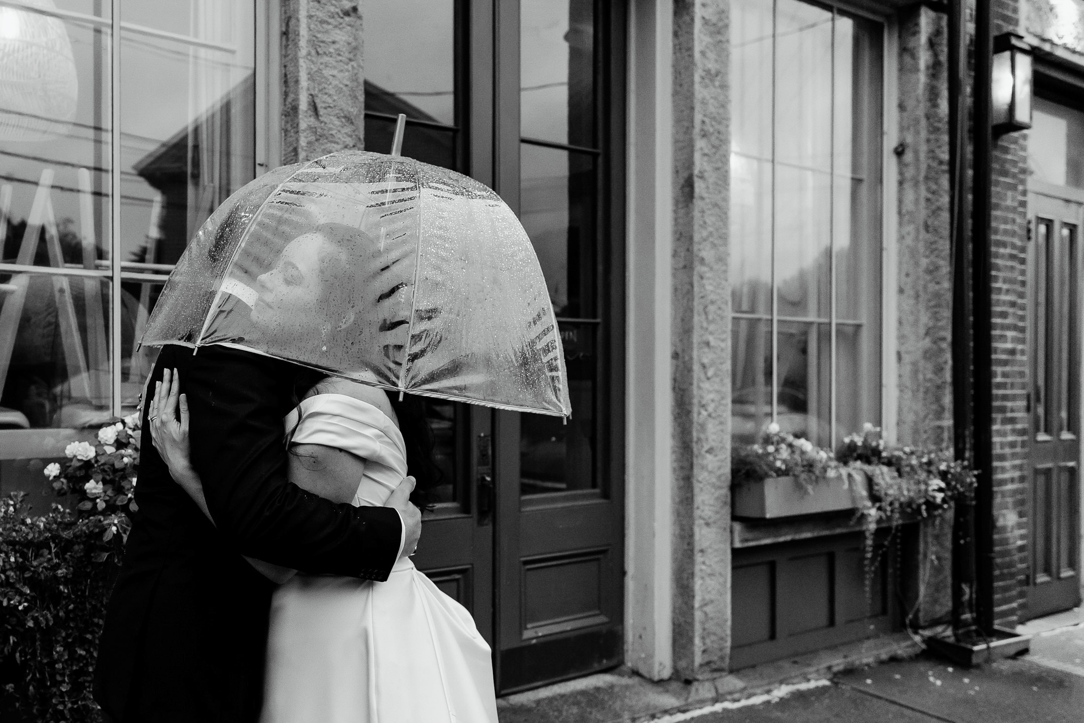 couple hugging under umbrellas during rainy Rockport Maine wedding